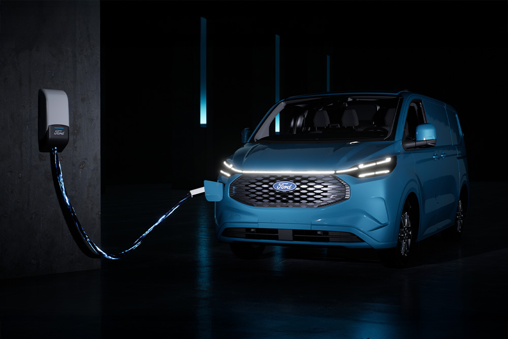 Un Ford E-Transit Custom bleu en charge à une borne de recharge.