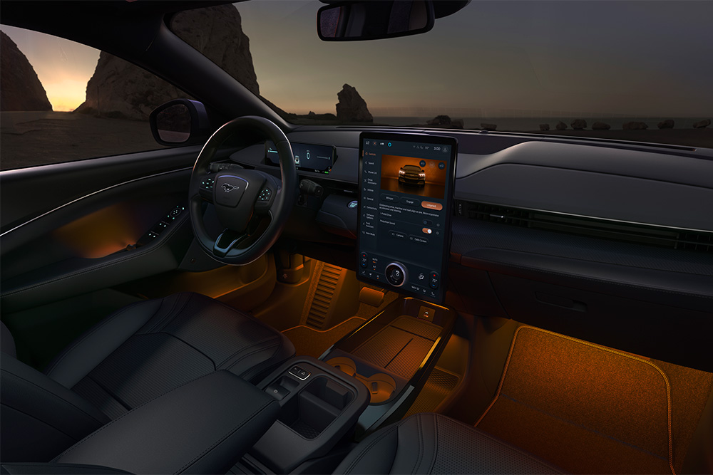 Ford Mustang Mach-E la nuit, avec l’écran tactile SYNC 4 de 15.5 pouces et l’éclairage d’ambiance à LED réglé sur la couleur orange.