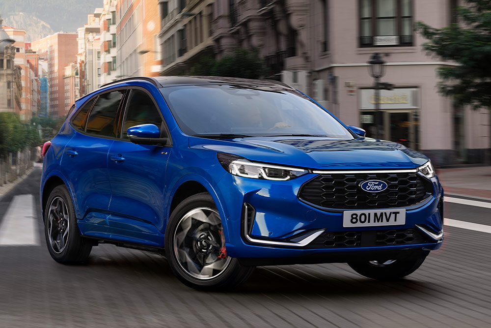 Vue avant d'un Ford Kuga bleu circulant dans une rue de la ville.