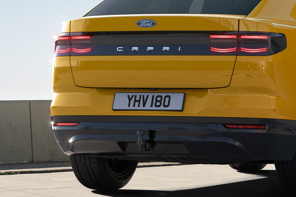 Vue arrière d'une Ford Capri® jaune roulant sur une route de ville.