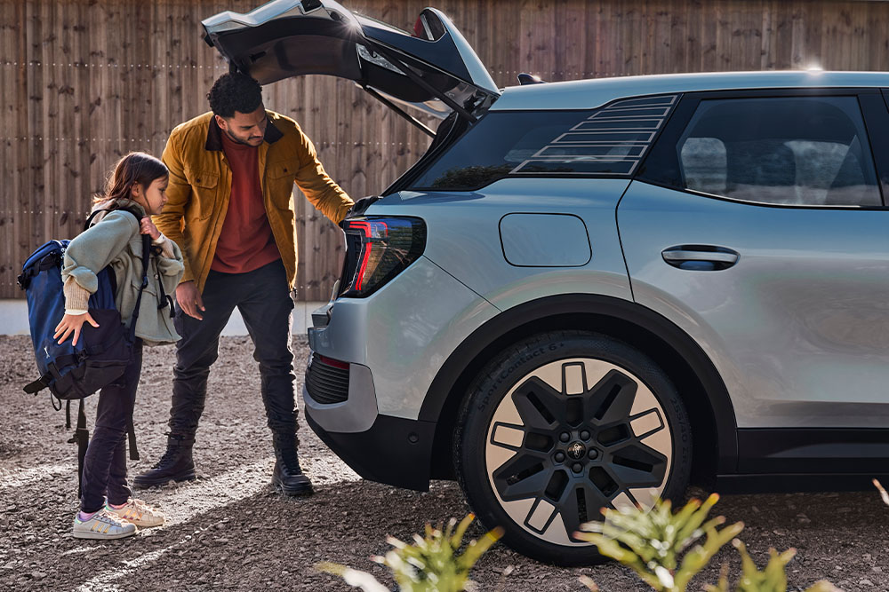 Ford Explorer en bleu. Une personne et un enfant chargent le coffre d’une Ford Explorer bleue..