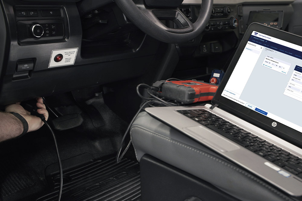 Vue rapprochée d'un ordinateur portable connecté au tableau de bord d'un véhicule Ford.