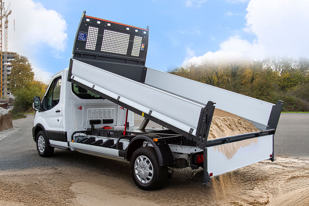 Châssis-cabine Ford Pro blanc avec plateau surélevé garé sur un chantier de construction.
