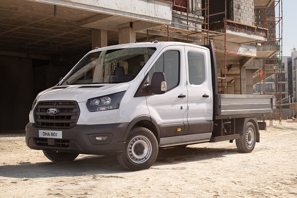 Châssis-cabine Ford Pro blanc garé sur un chantier de construction à côté de deux ouvriers du bâtiment.