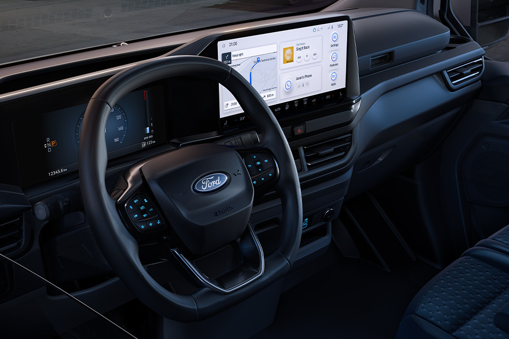 Vue intérieure d'un véhicule Ford avec un grand tableau de bord numérique, montrant un chantier à travers le pare-brise.