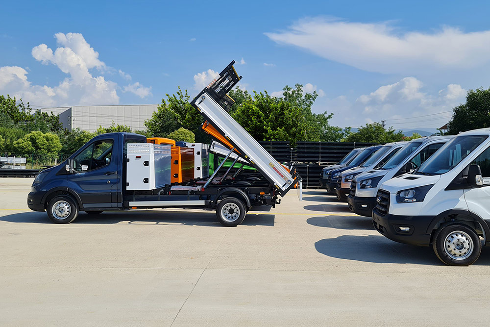 Une flotte de véhicules Ford E-Transit à châssis squelette garés sur un terrain.