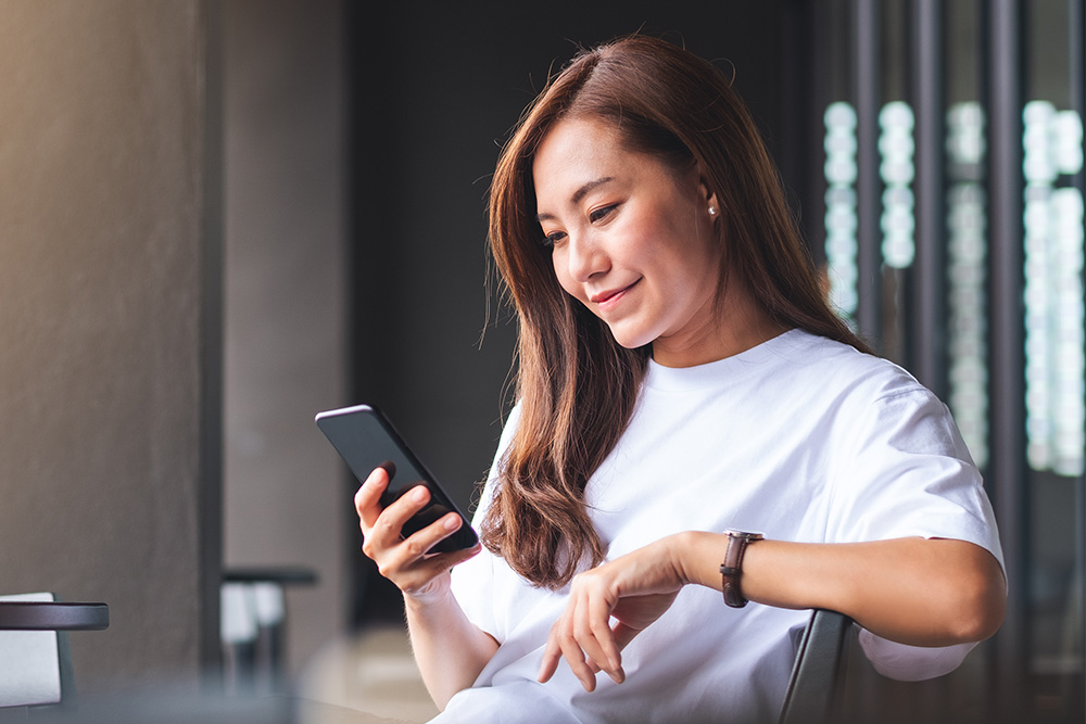 Femme consultant les alertes en temps réel de l'application FordPass sur son appareil mobile.