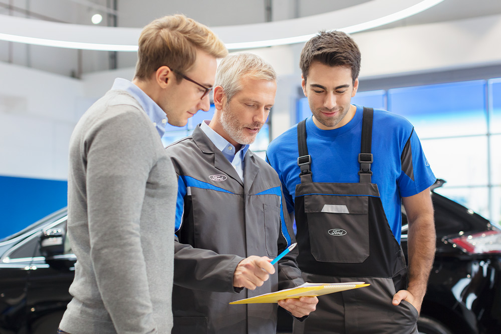 Trois experts discutent des options de véhicules prêts à l'emploi dans un Ford Transit Centre.