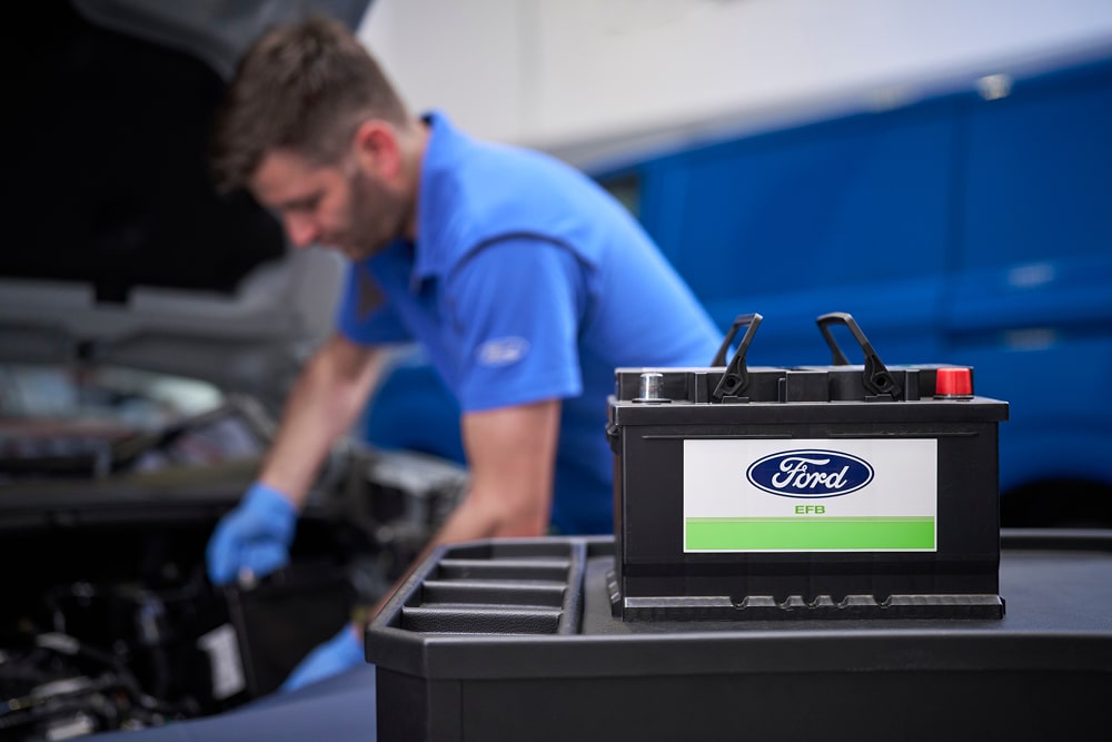 Batterie de voiture Ford avec un technicien en arrière-plan travaillant sur un véhicule