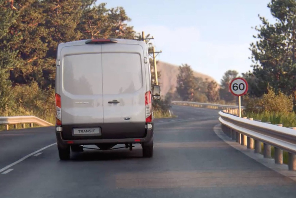 Ford Transit Van roulant sur une route, avec panneau de signalisation, vue de l’arrière